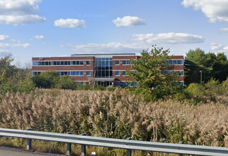 A three-story office building sits beyond a marsh