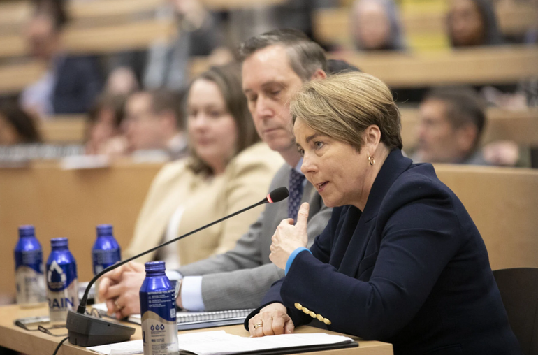 Women in suit sits at table with microphone
