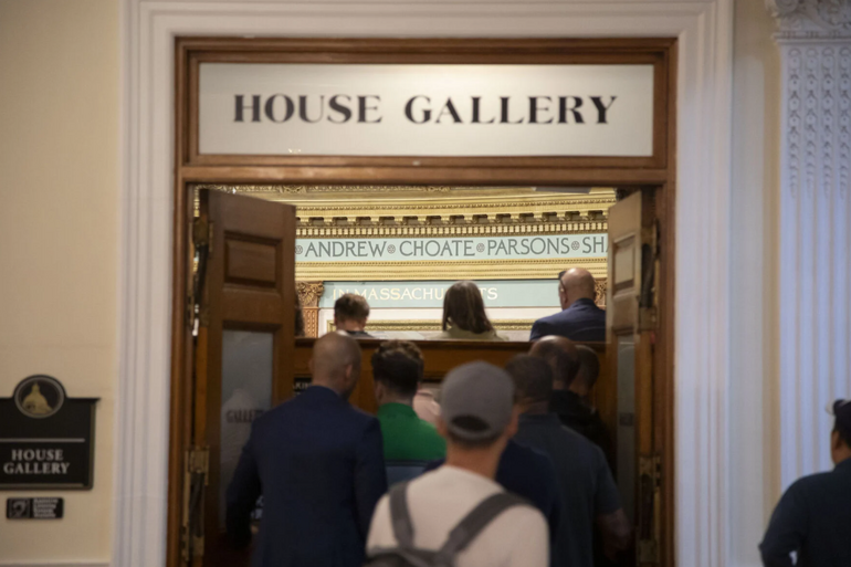 People seen from behind entering through a double door labeled 