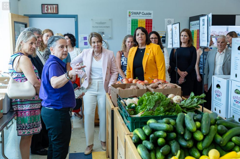 A group of people stand near large boxes of produce
