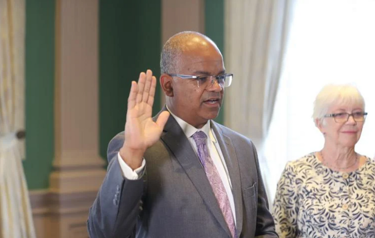 Man in suit with glasses raised hand to take pledge
