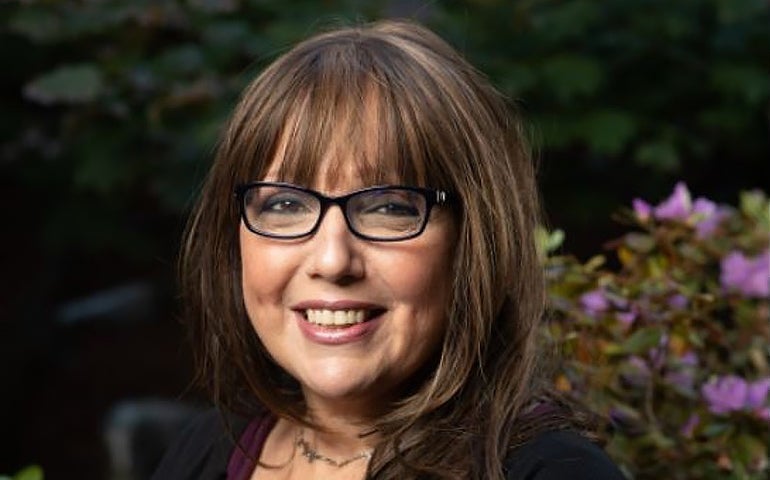 Elyse Semerdjian, smiling with trees and purple flowers in the background