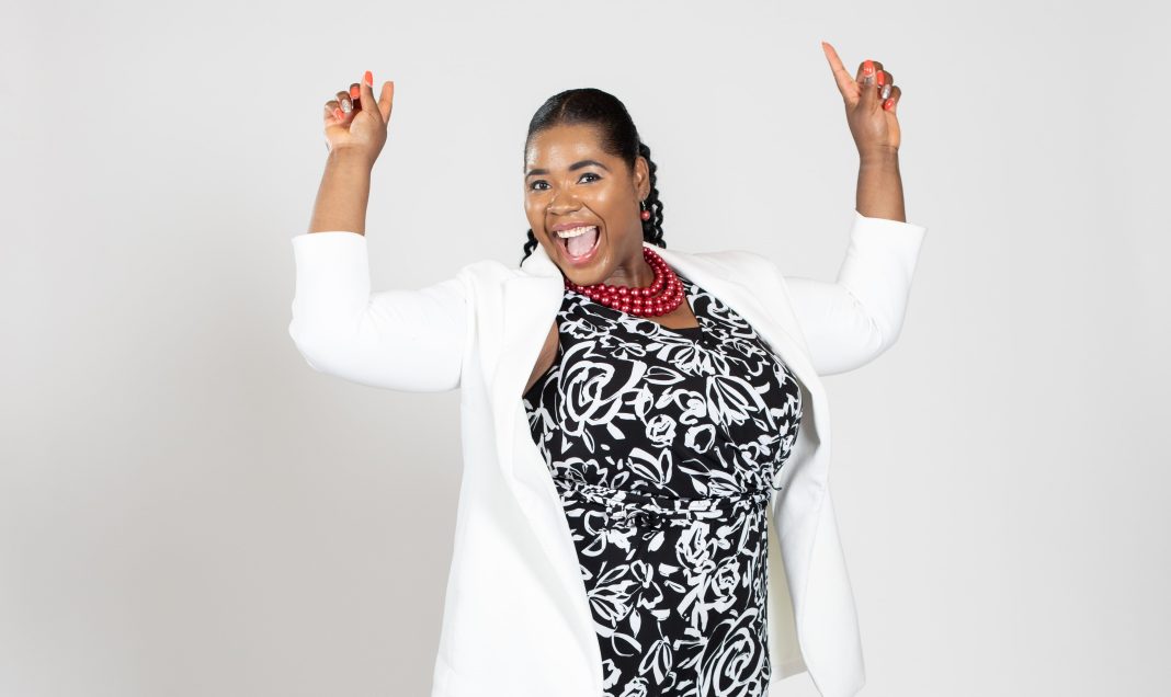 A woman wears a white jacket over a black flower-print dress.