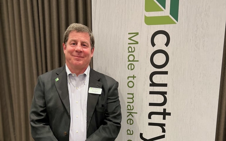 A man in a suit stands in front of a Country Bank sign