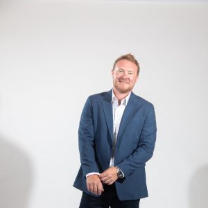 A man in a suit smiles as he adjusts his sleve