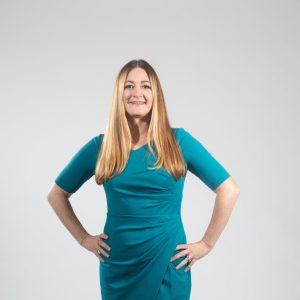 A woman in a green dress with hands on hips smiling