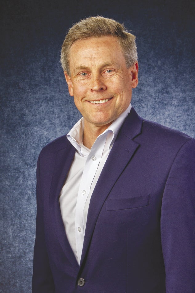 A man in a suit in front of a blue background