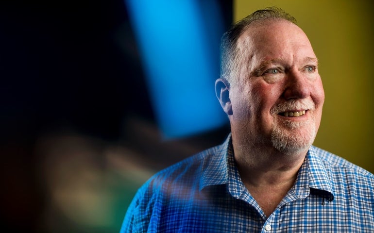 A man in a blue-checked shirt gazes off to the viewers right