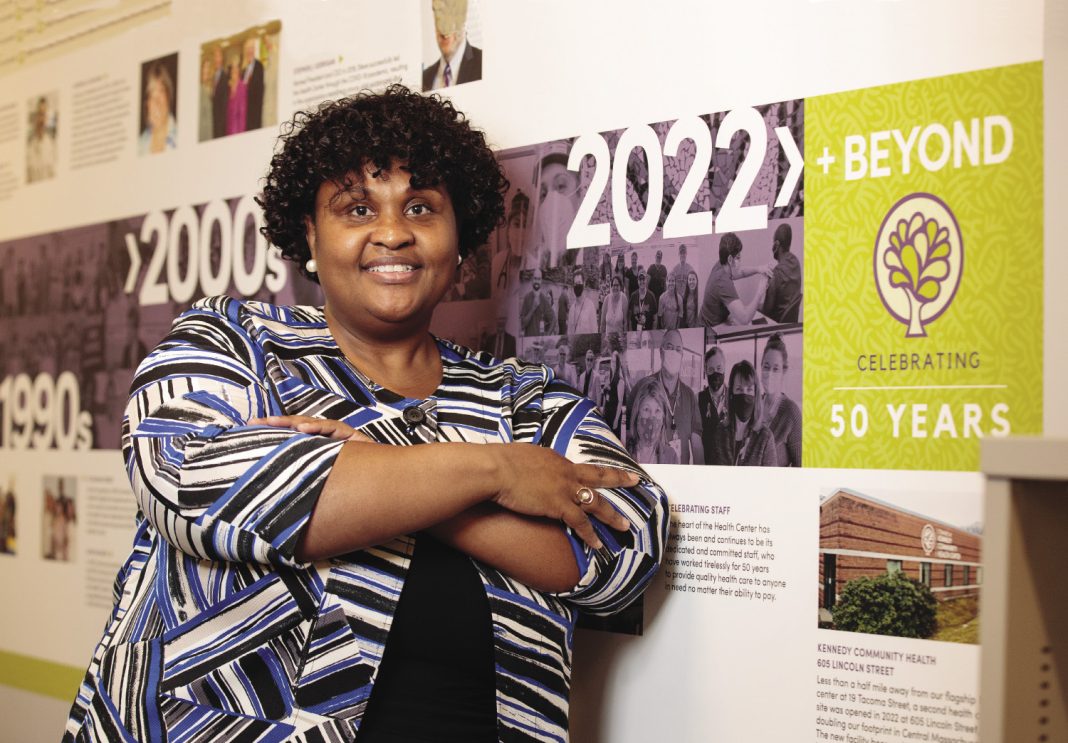 A woman leans against a wall with posters on it.