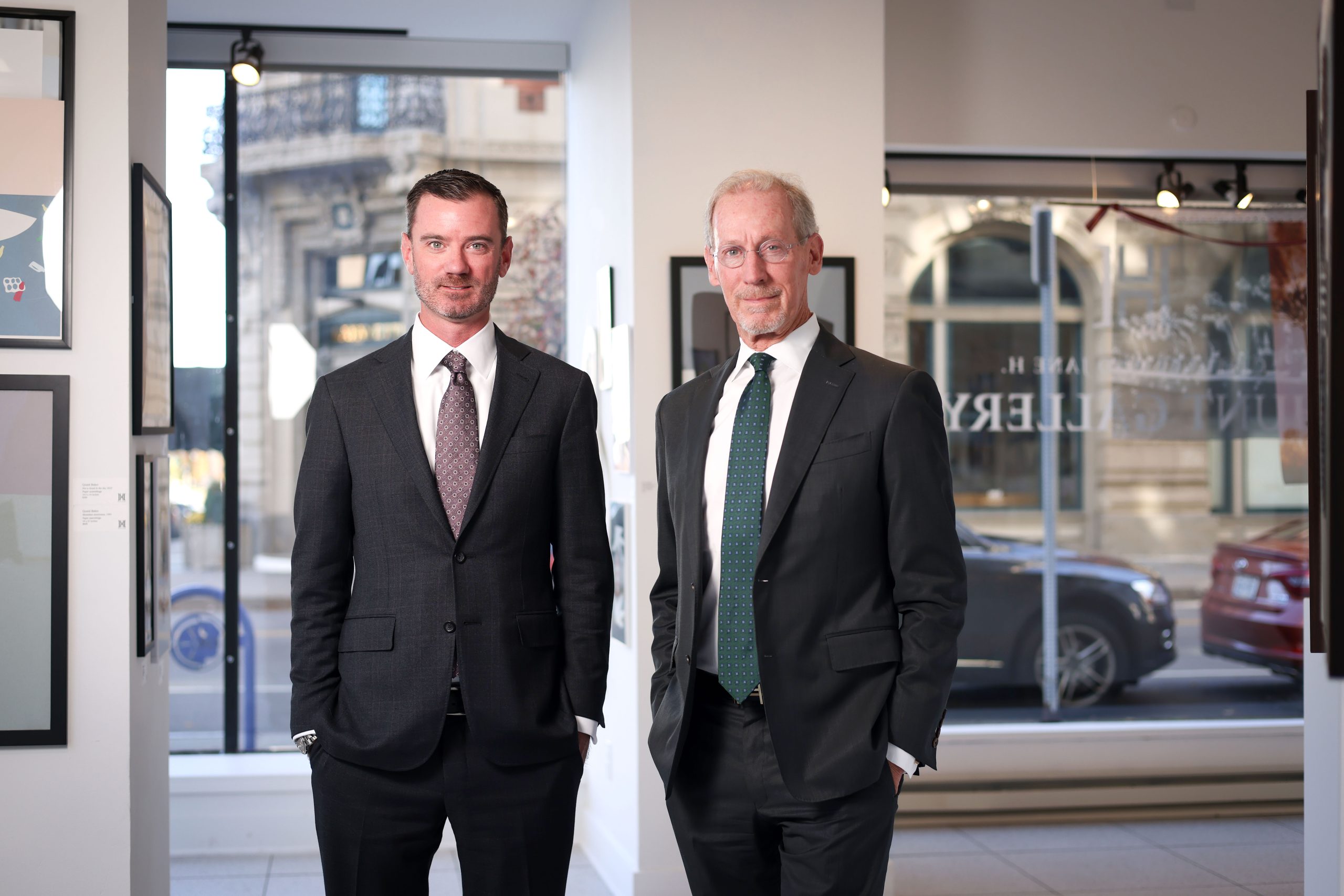 Charlie and Peter Hunt Two men in suits stand in front of first-floor window showing a streetscape