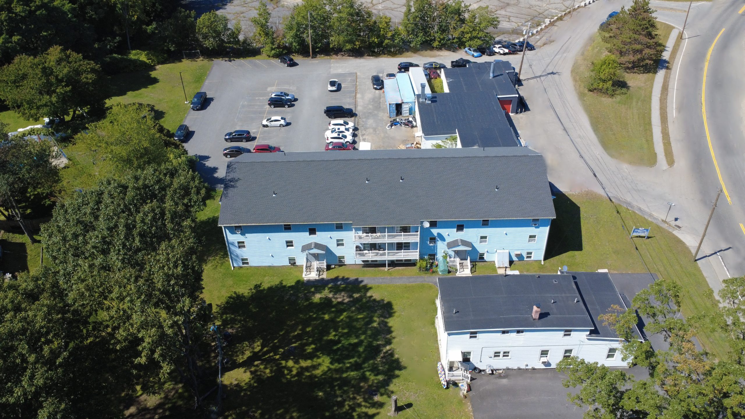 Aerial view of a blue, three-story apartment building with parking lot behind