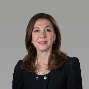 Headshot of a woman with shoulder-length brown hair, wearing a black top