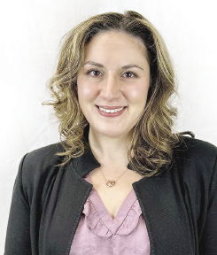A woman wears a pink shirt with a black jacket.