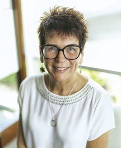 A woman wears large black glasses and a white blouse.