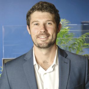 A man wears a dark blue blazer and white button down.