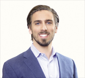 A man wears a blue suit jacket and light blue button down.