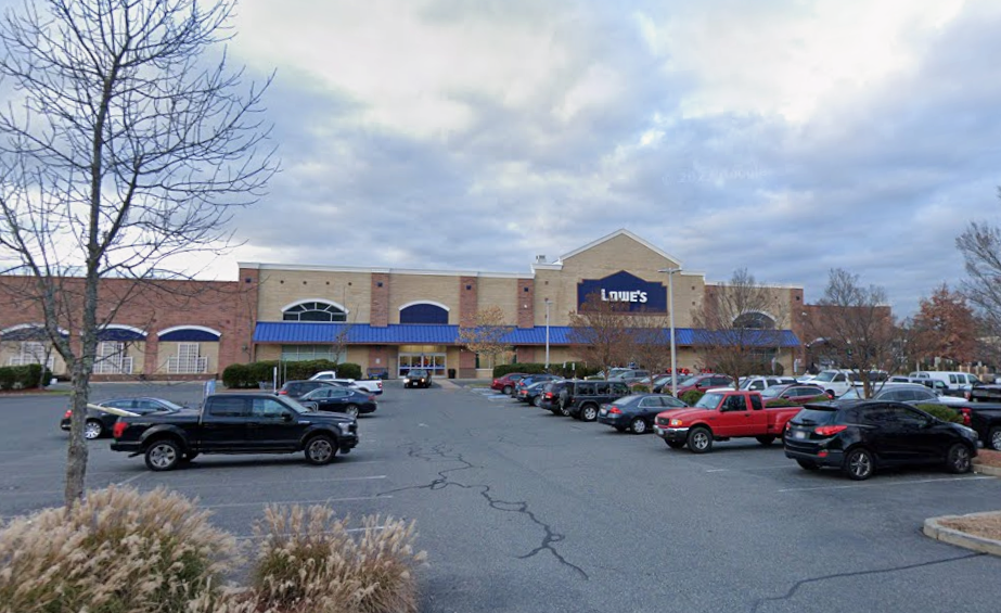 The exterior of a large retail store front with a parking lot in front of it.