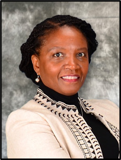 A headshot of a woman wearing a black turtle neck and a white and black jacket