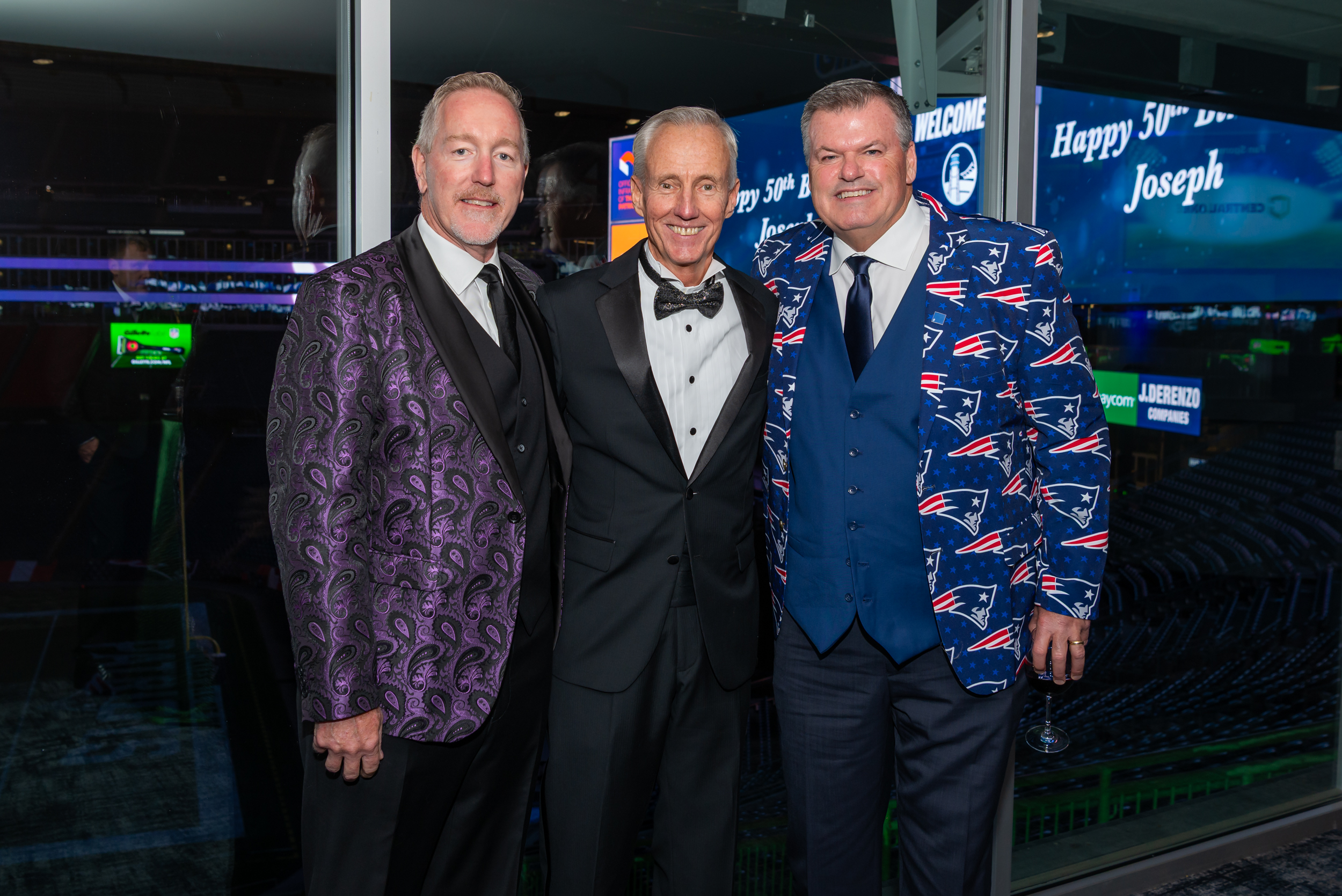 Three men stand together wearing suits.