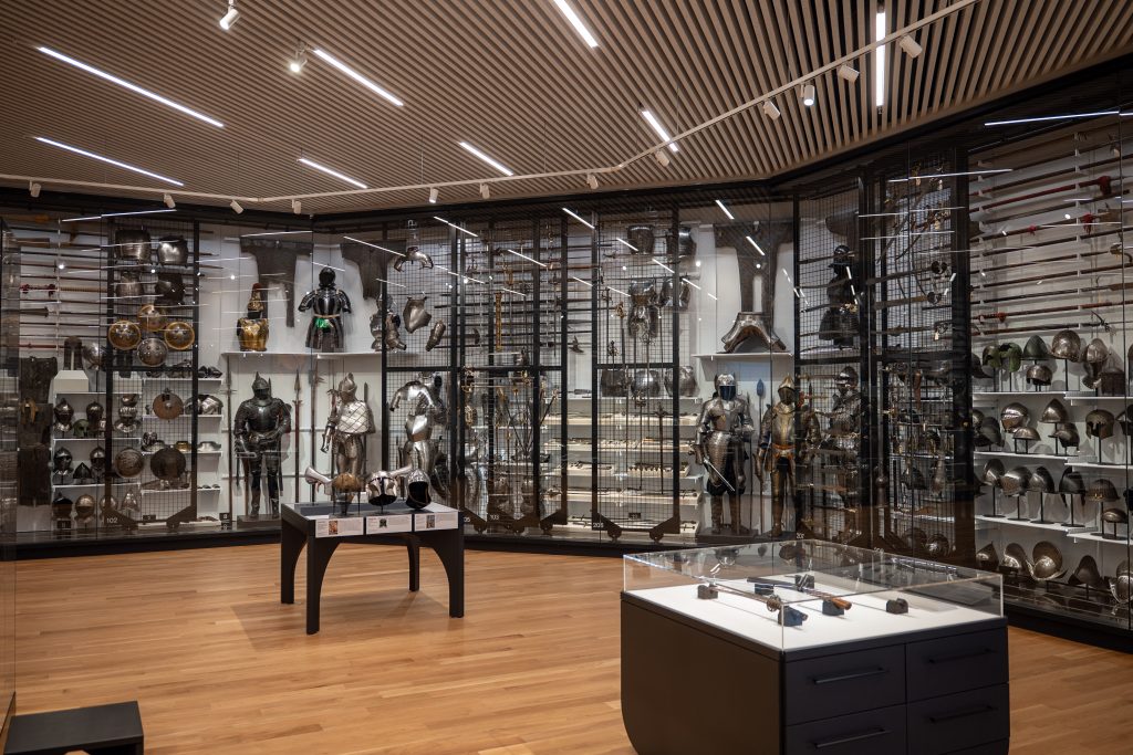 A large glass display with hundreds of antique weapons and armor