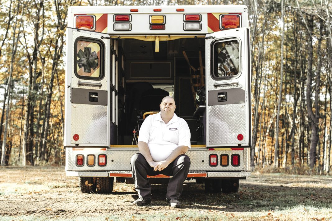 A man sits on the back of an ambulance.