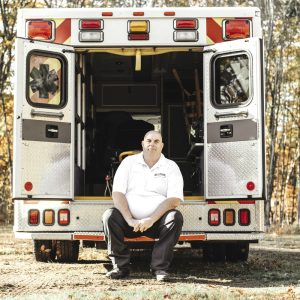 A man sits on the back of an ambulance.