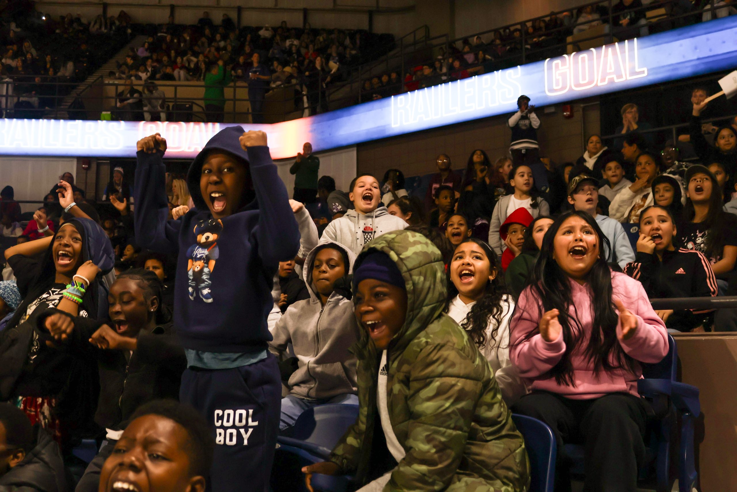 A group of school-age children celebrate in a hockey arena.