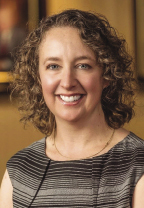 A woman with short, curly blonde hair wears a striped top.