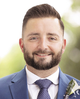 A headshot of a man with light brown hair, beard, and mustache