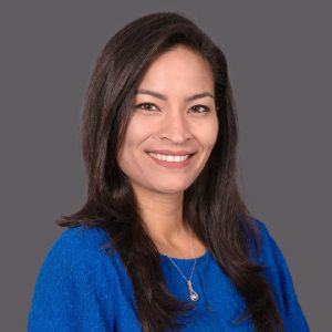 A woman with long, dark, straight hair wears a blue top.