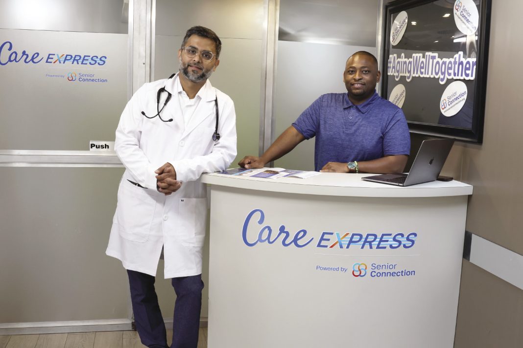 Two men stand inside a mobile care van leaning on a font desk.
