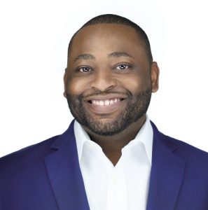 A man wears a blue blazer and white button down shirt.