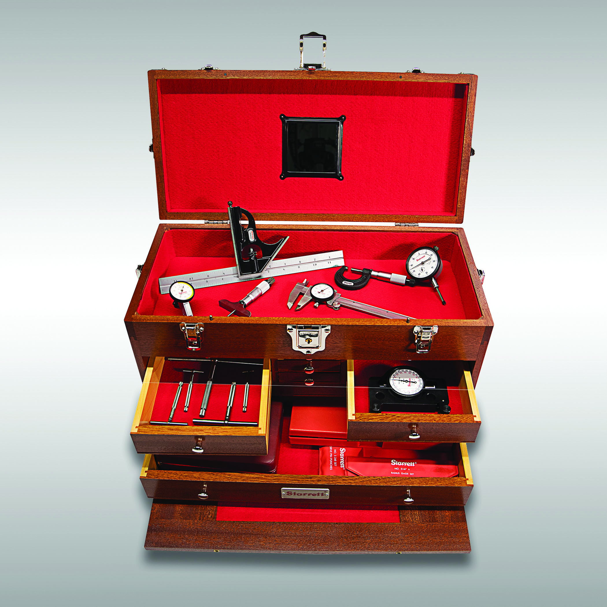 A wooden tool box, with multiple drawers open, showing a red velvet lining and tools.