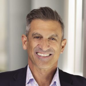 A headshot of a man with grey and white hair