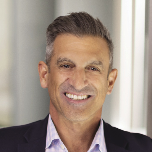 A headshot of a man with grey and white hair