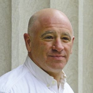 A bald man wears a white button down.