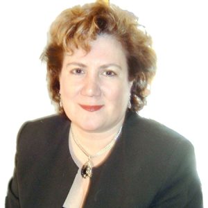A woman with short blonde hair wears a black top with a silver and black necklace.