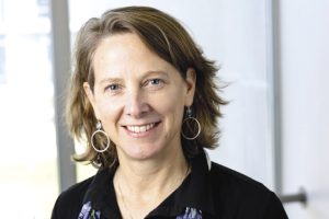 A woman with short dirty-blond hair wears a black top.