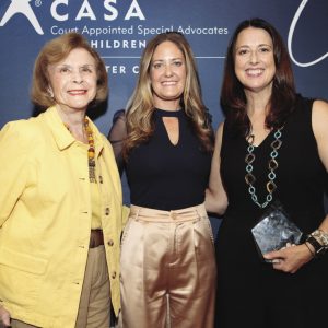 Three women stand together linking arms