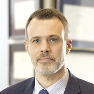 A photo of a man with short brown hair and a gray beard