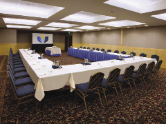 Inside a meeting room with tables in a C formation and chairs along the outside of them