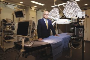 A man stands inside a lab with lights and computers.