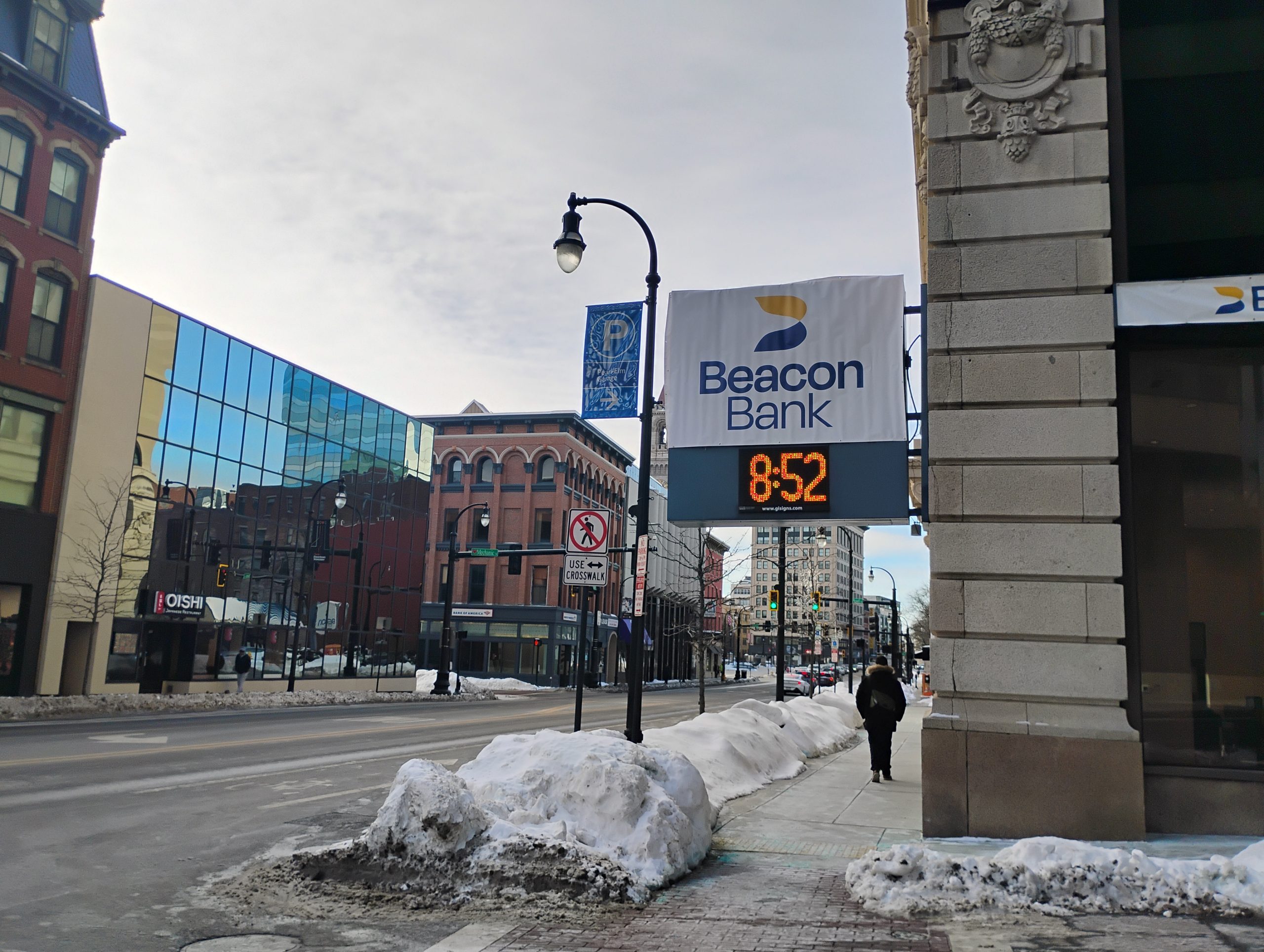 A Beacon Bank sign overhanging a sidewalk in an urban setting