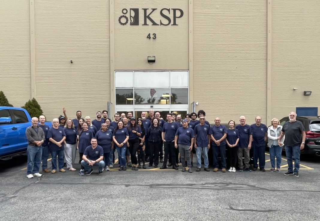 A group of people in dark blue t-shirts stand together in a line.