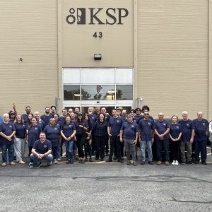 A group of people in dark blue t-shirts stand together in a line.