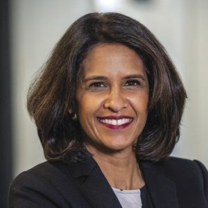 A woman with shoulder-length brown hair wears a black blazer. 