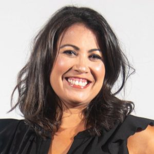 A woman with shoulder-length dark hair wears a black dress.