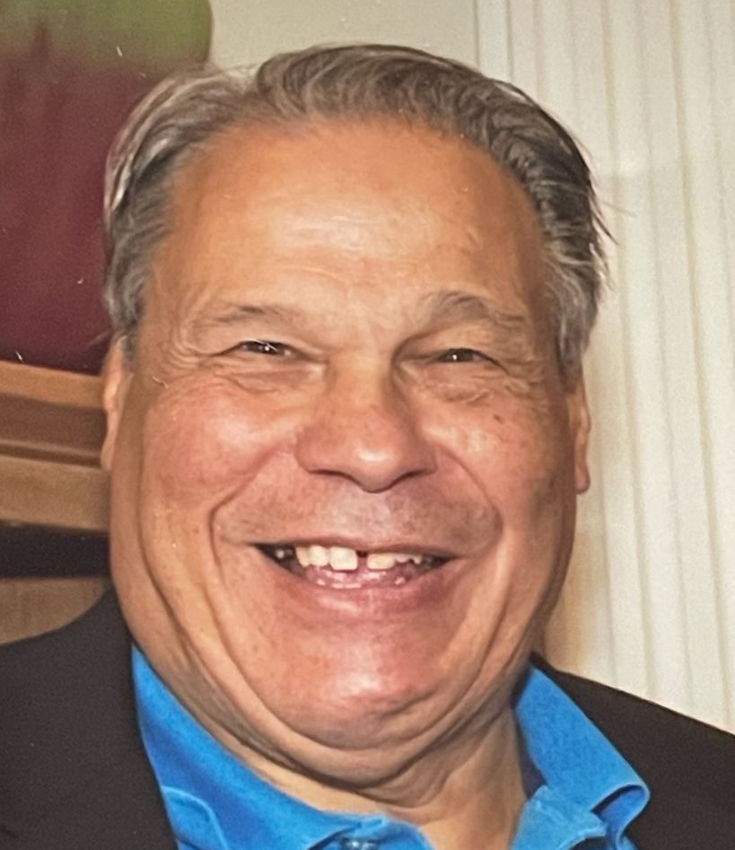 Man in black suit with blue shirt smiles for photo